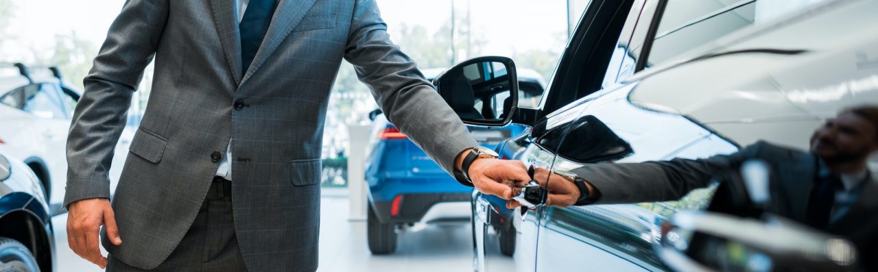 Panoramic Shot Of Man Opening Car Door In Car Showroom.jpg